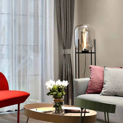 Modern living room with a red chair, gray sofa, and a small round table with flowers.