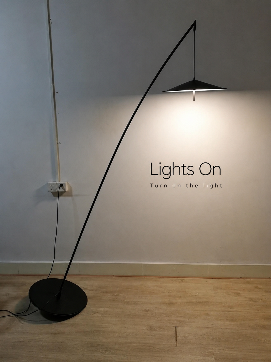 Modern black floor lamp on a wooden floor with a plain wall background